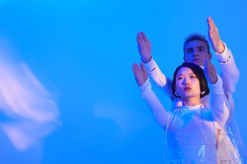 Artificial Intelligence Generator Art - Learn The Power of Models 6 Young Man and Woman in Futuristic Clothing Standing in a Studio with Blue Lighting and Holding Their Arms Up