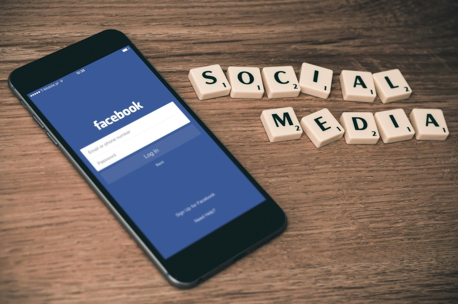 Effective Local Internet Advertising Tactics to Drive Traffic and Sales 2 space gray iPhone 6 with Facebook log-in display near Social Media scrabble tiles