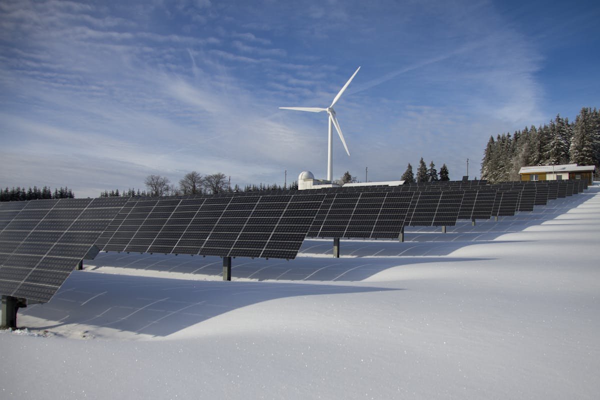 Innovations in Renewable Energy: Powering the Future 2 Solar Panels on Snow With Windmill Under Clear Day Sky